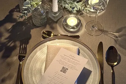 Winietka z kodem QR na talerzu przy nakrytym weselnym stole.